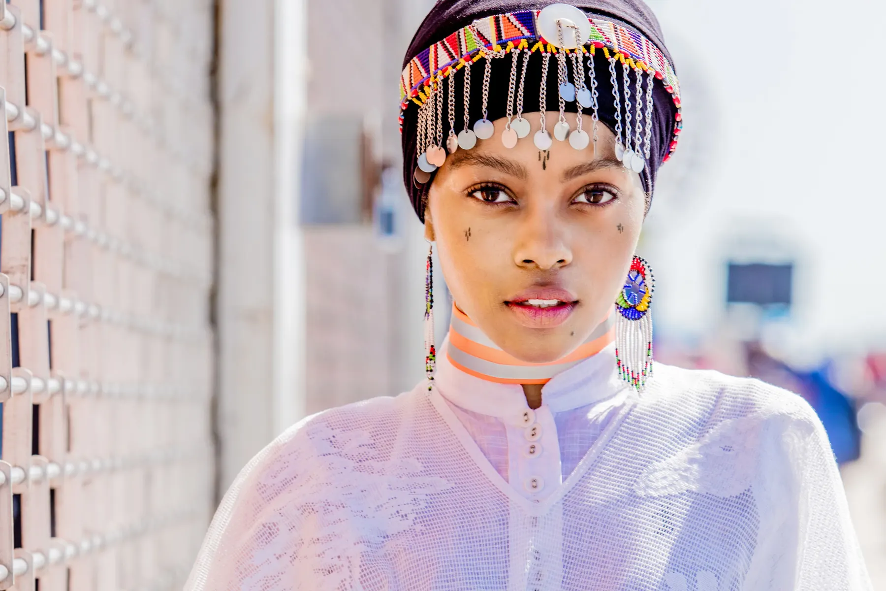 A young woman in a beaded Ndebele headpiece, looking directly at the camera.