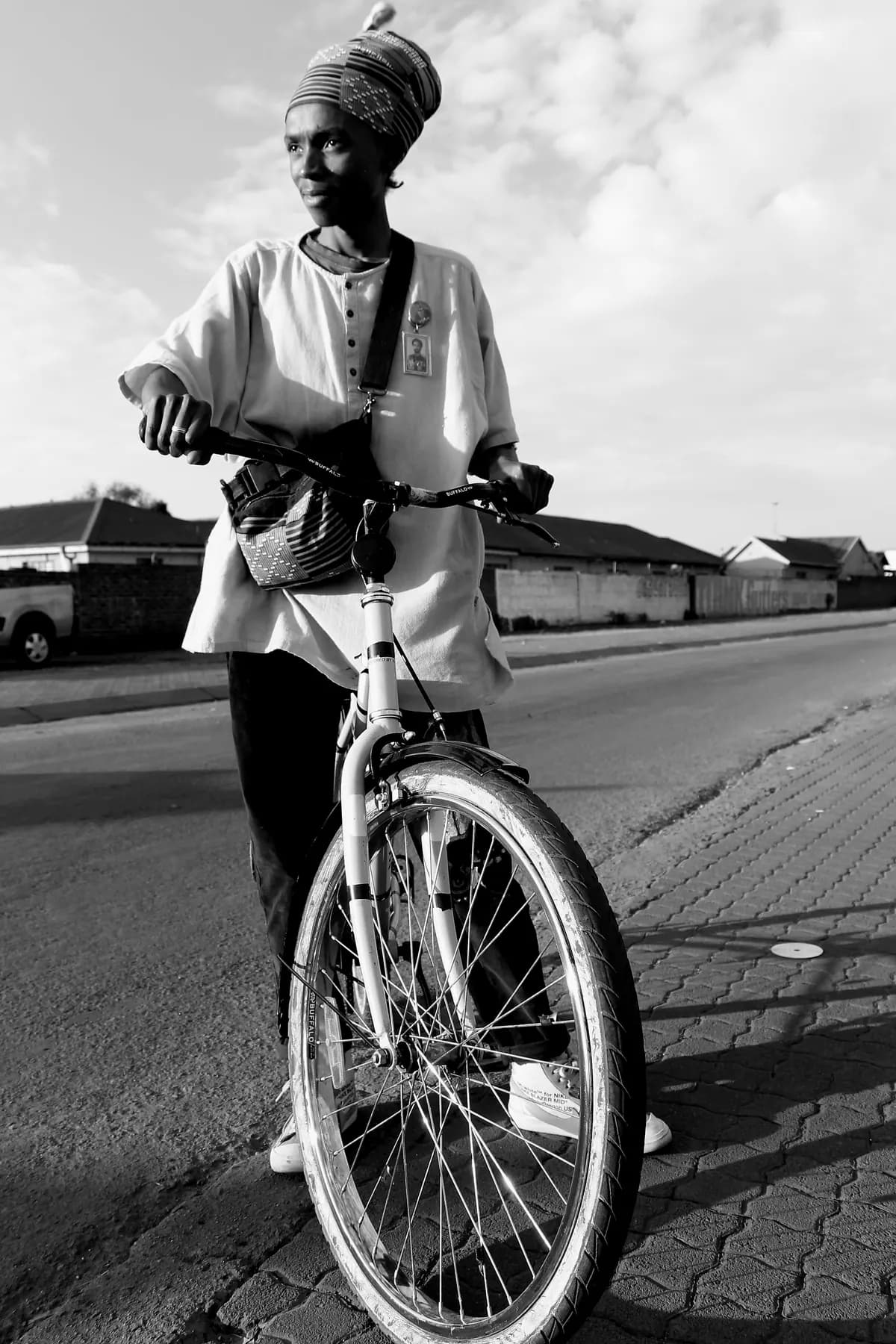 A woman with her bicycle on a township street in the late afternoon.
